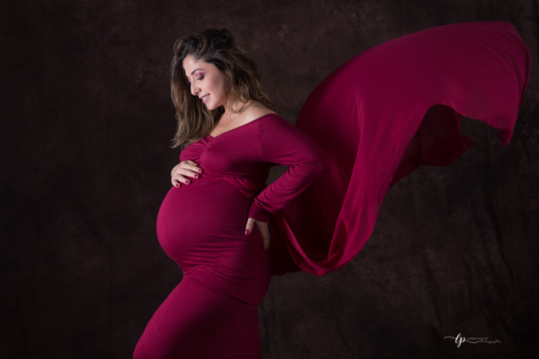 Future maman et son ventre rond avec jolie robe de grossesse rouge écarlate