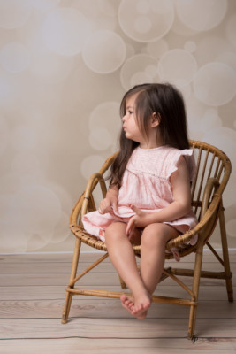 Petite fille assise sur chaise en osier